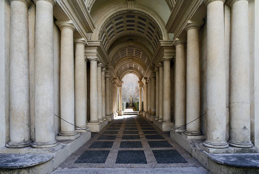 A frontal view along Palazzo Spada’s short forced-perspective colonnade, towards a small statue.