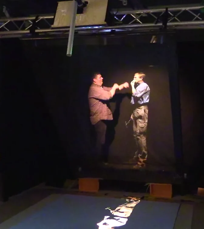 A Pepper’s Ghost workshop display with a video screen and a reflected figure.